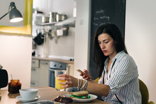 Young Woman Texting Message While Having Breakfast At Her Home
