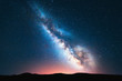 Milky Way. Fantastic night landscape with bright milky way, sky full of stars, yellow light and hills. Shiny stars. Picturesque scene with our universe. Space background. Amazing astrophotography