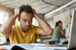 © wayhome.studio  - Stressed young African American student of school of economics feeling frustrated while working on diploma project, sitting at coworking space in front of open laptop computer, holding head with hands