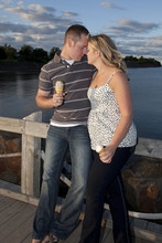 Young In Love Engaged Couple With Ice Cream On The Boardwalk.