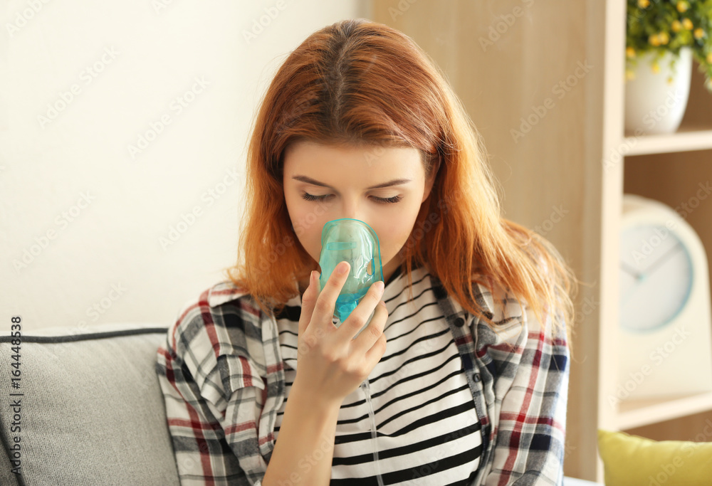 Young woman using nebulizer for asthma and respiratory diseases at home