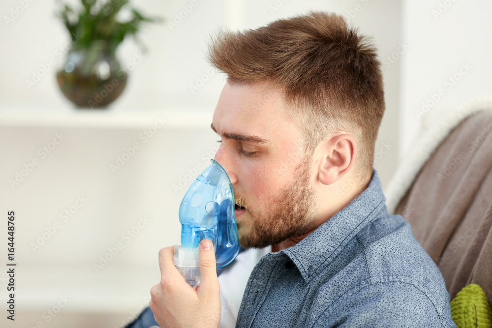 Young man using nebulizer for asthma and respiratory diseases at home