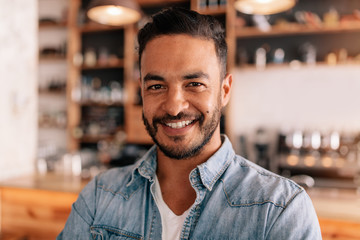 Wall Mural - Smiling young man in a coffee shop