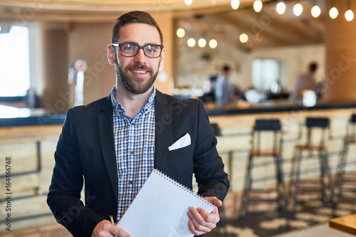Fotografía Businessman with notepad looking at camera in restaurant
