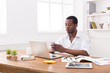 © Prostock-studio - Young african-american businessman texting on phone while working on laptop