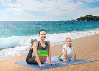 Wall Mural - Mother and daughter practicing yoga on beach