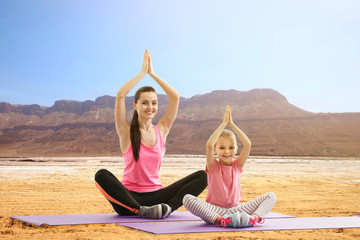 Wall Mural - Mother and daughter practicing yoga outdoor