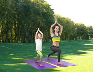 Wall Mural - Mother and daughter practicing yoga in park