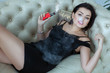 © Petro - Woman lying on the sofa smoking an electronic cigarette and exhaling steam.