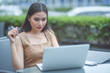 Sharing good business news. Attractive young woman talking on the mobile phone and smiling while sitting at her working place in office and looking at laptop, businesswoman working. Selective focus.