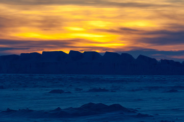 Wall Mural - The frozen Weddell Sea in Antarctica at sunset with icebergs in the disdance.
