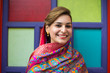 Smiling young Pakistani lady in front of a colorful door