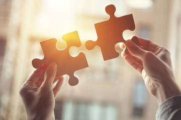 businesswoman hand connecting jigsaw puzzle with sunlight effect, business solutions, success and st