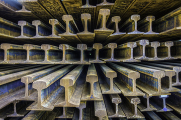 Perspective view of pile of rusty rails. They are a flat-bottomed type.