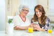 © Bojan - Grandmother and granddaughter commenting social media feeds on smart phone.