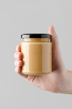 Peanut / Almond / Nut Butter Jar Mock-Up - Male Hands Holding A Nut Butter Jar On A Gray Background