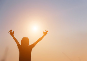 Silhouette of woman praying over beautiful sky background