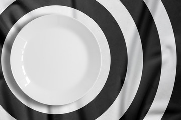 Top view of empty food plate put on tablecloth., The tablecloth is stripe pattern punctuate black and white with copy space.