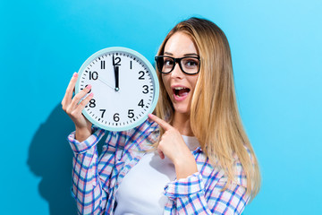 Young woman holding a clock showing nearly 12