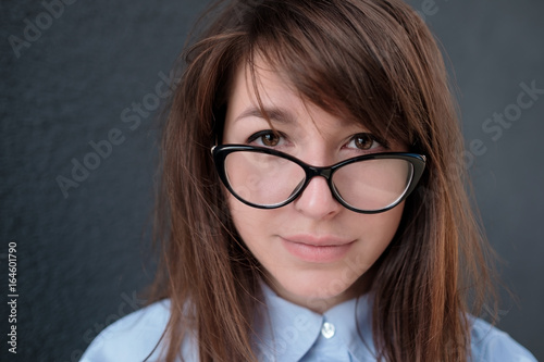 Fotografie, Obraz Closeup portrait of young attractive woman with glasses on a dark background
