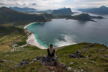Wall Mural - Woman enjoying an amazing view towards Haukland Beach on the Lofoten Islands during summer in Norway