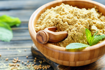 Wall Mural - Wooden scoop in bowl with the mustard powder.