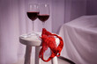 Lace panties, condom and glasses with wine on stool in bedroom. Sex concept