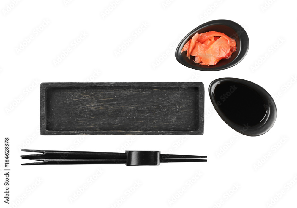 Wooden board, chopsticks, soy sauce and pickled ginger on white background
