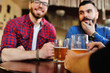 © Evgeniy Kalinovskiy - Friends clink glasses of beer glasses close-up on the background of the pub