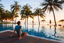 Happy Holidays In Beautiful Beach Hotel At Sunset, Man Sitting Near Swimming Pool And Relaxing
