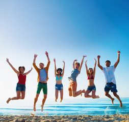 Happy smiling friends jumping at the beach