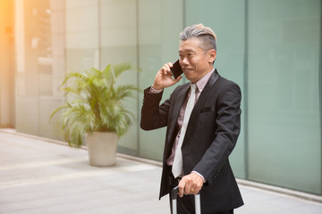 asian senior businessman travel with phone