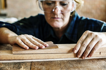 Wall Mural - Woman carpenter using sandpaper on a wood