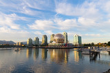 Fototapeta  - Golden sunset at False Creek in Vancouver with a view on Science World and mountains. Urban sunset with landmark reflection in the water.