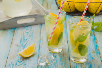 Wall Mural - lemonade with mint on rocks served in a glass with a straw