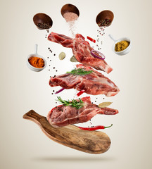 Wall Mural - Flying raw pork steaks with ingredients, food preparation concept