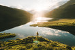 © Michael Schauer - Young male standing in front of a warm summer sunrise reflection of the sky at a mountain lake.