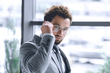 Wall Mural - portrait of confident stylish businessman in eyeglasses and suit looking at camera