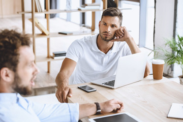 Canvas Print - portrait of young businessman with laptop on meeting with coworkers in office