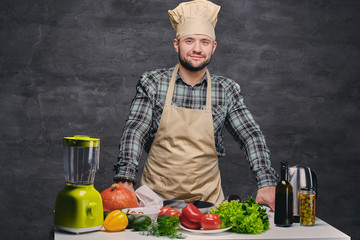 Wall Mural - Chef cook posing near the table with a lot of fresh vegetables.