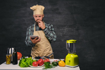 Wall Mural - Bearded male chef cook looking in the tablet PC.