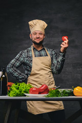 Wall Mural - Chef cook posing near the table with a lot of fresh vegetables.