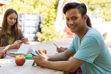 Canvas Print - Smiling young multiethnic friends students using mobile phones