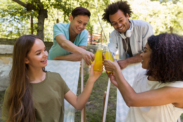 Canvas Print - Happy young multiethnic friends students outdoors drinking juice