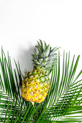  Pineapple and palm branch on white background top view copyspace