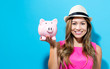 © Tierney - Young woman with a piggy bank on a blue background