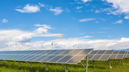 Panels of the solar energy plant under the blue sky with white clouds - clean energy concept