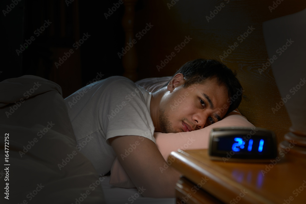 Depressed man suffering from insomnia lying in bed - obrazy, fototapety, plakaty 