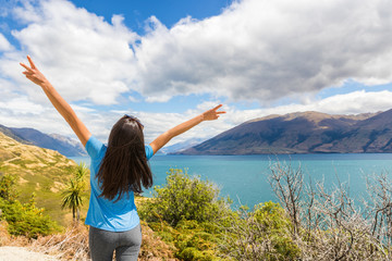 Fototapete - New Zealand travel happy tourist woman with arms up at Wanaka lake nature landscape outdoors. Wanderlust adventure young girl with peace hand sign.