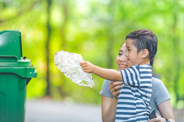 Cute little boy are dumping trash in a recycle bin